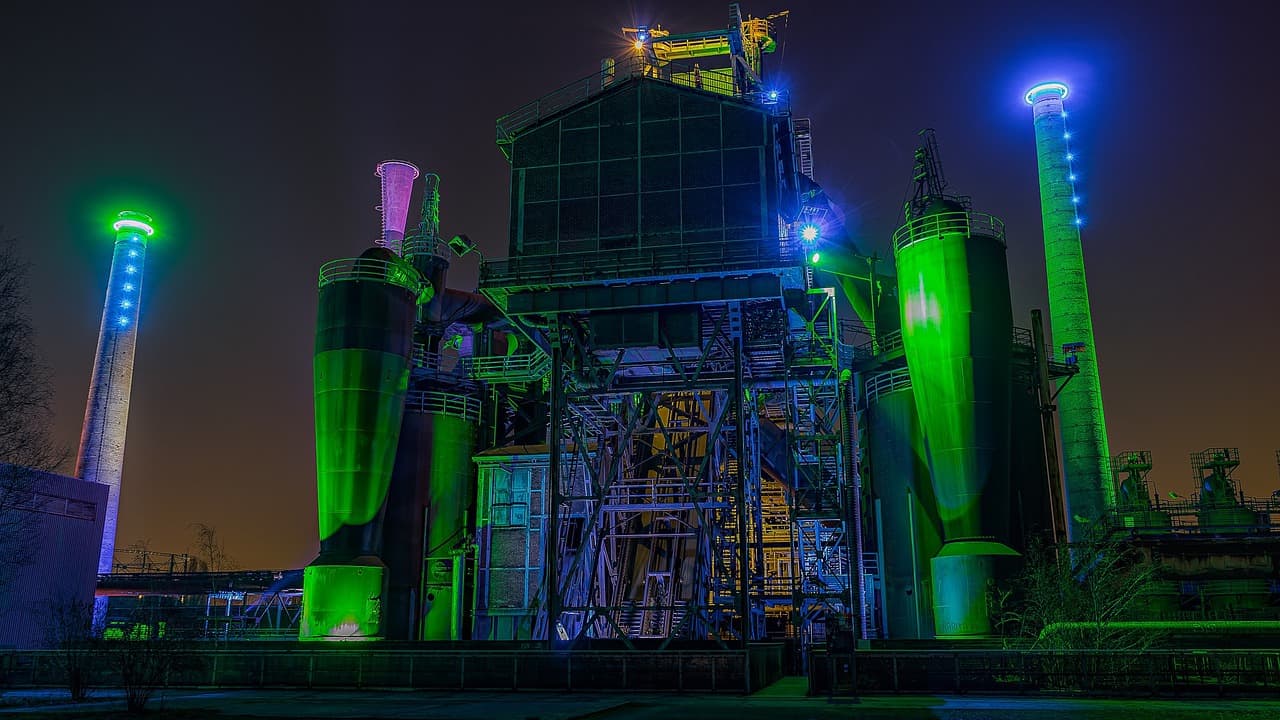 A powerstation lit up at night in green and blue lights
