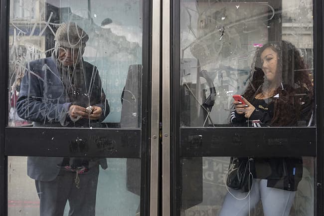 Street photography, people standing in old telephone boxes