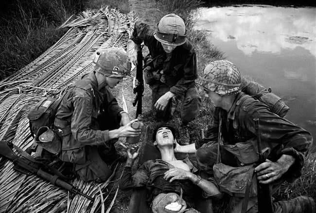 VIETNAM. 1968. RGI with wounded Vietcong.