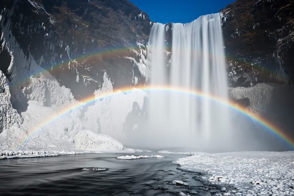 Waterfall with double rainbow in winter. Skógafoss, Iceland. Photo: Jeremy Walker
