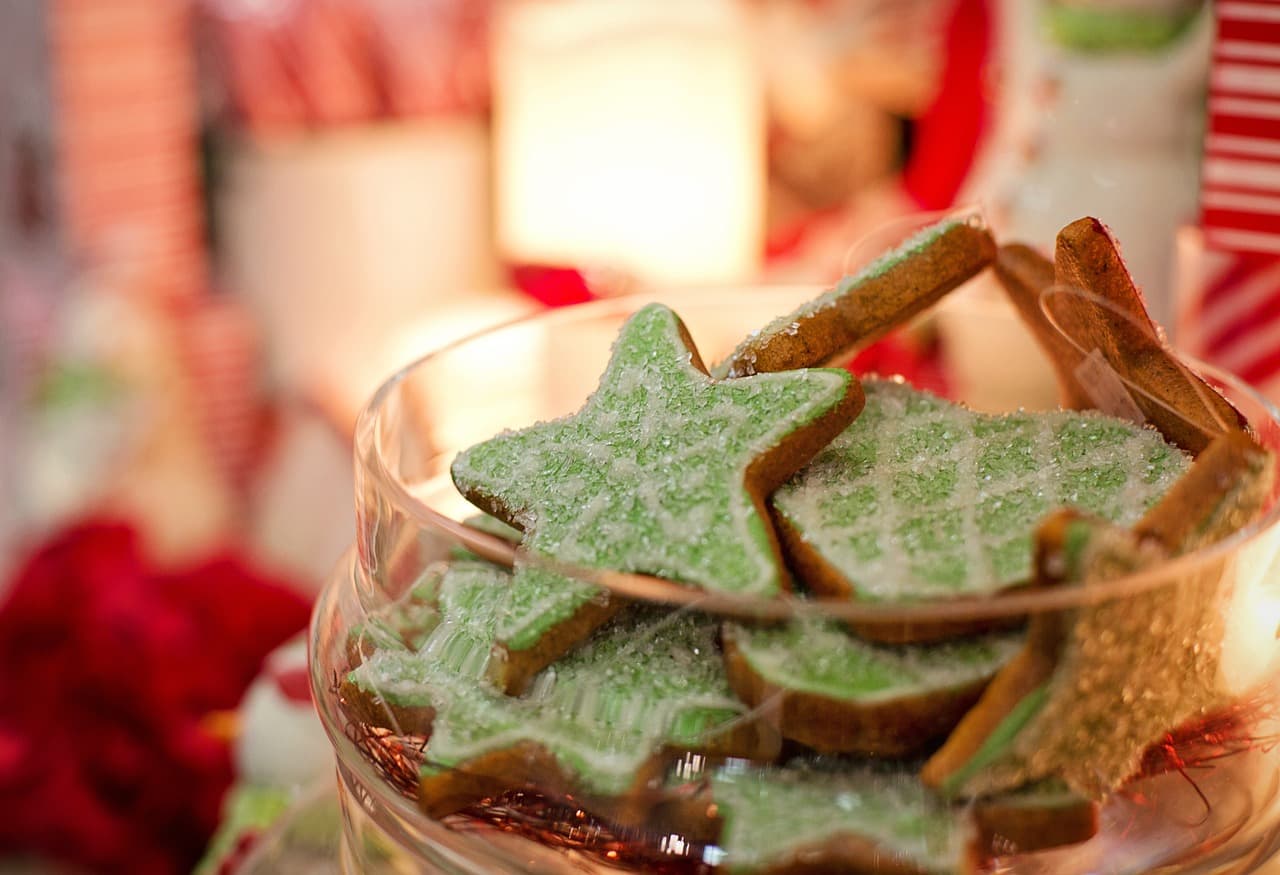 bowl of christmas cookies in the shape of stars with green icing