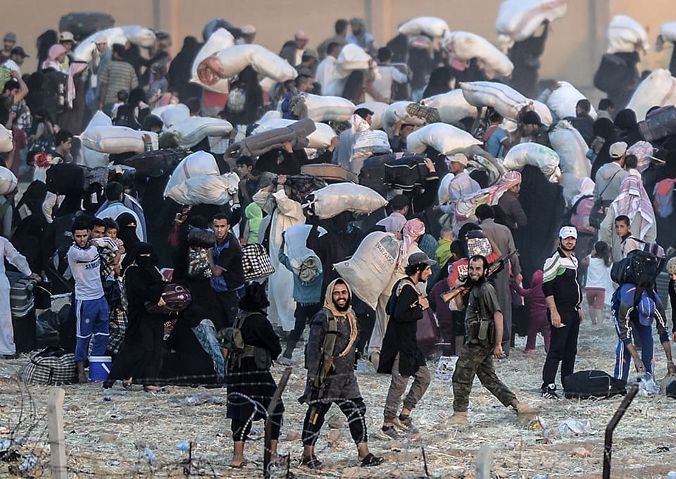 Islamic State members ask people to go back to city center at the Turkish Akcakale crossing gate in Sanliurfa province, on June 13, 2015. Turkey said it was taking measures to limit the flow of Syrian refugees onto its territory after an influx of thousands more over the last days due to fighting between Kurds and jihadists. Under an "open-door" policy, Turkey has taken in 1.8 million Syrian refugees since the conflict in Syria erupted in 2011. AFP PHOTO / BULENT KILIC / AFP / BULENT KILIC