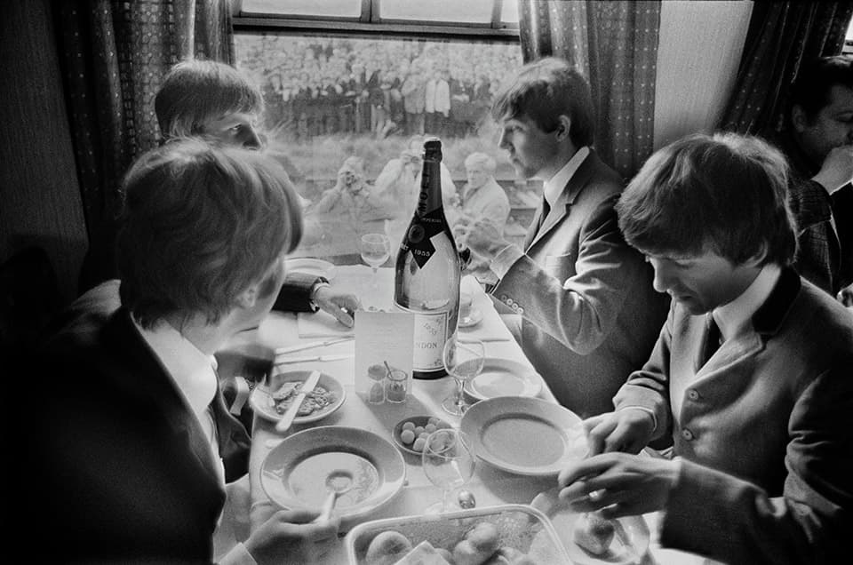 G.B. ENGLAND. LONDON. The BEATLES during filming of 'A Hard Days Night'. John, Paul, George and Ringo take time off, during the making of the film 'A Hard Days Night', for a meal on the train. Thousands of fans lined the route. 1964.