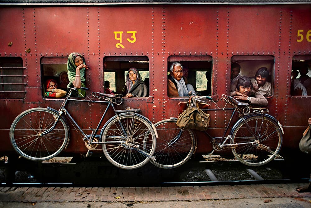 Steve McCurry West Bengal 1983. Bicycles hang on side of train