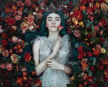 Woman with green hair and a crown lying in a bed of rose from an aerial view