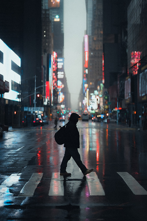 person crossing city street at night