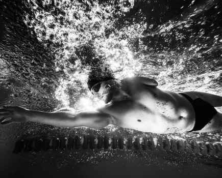 Underwater capture of a swimmer moving in cap and googles in black and white