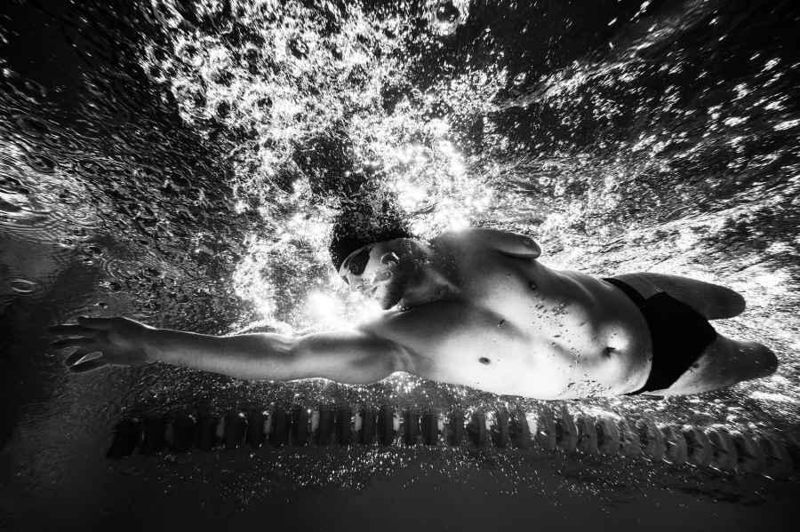 Underwater capture of a swimmer moving in cap and googles in black and white