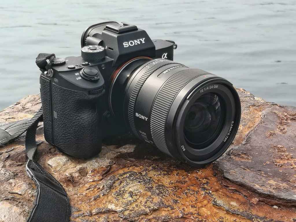 Sony FE 24mm F1.4 GM black camera sat on a rock