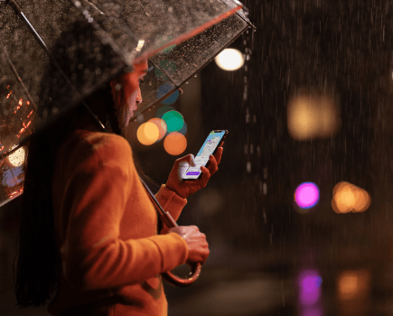 Girl in yellow jumper under a clear umbrella in the dark on iphone