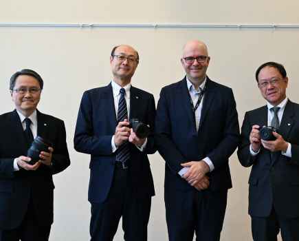 four men in suits and ties holding cameras