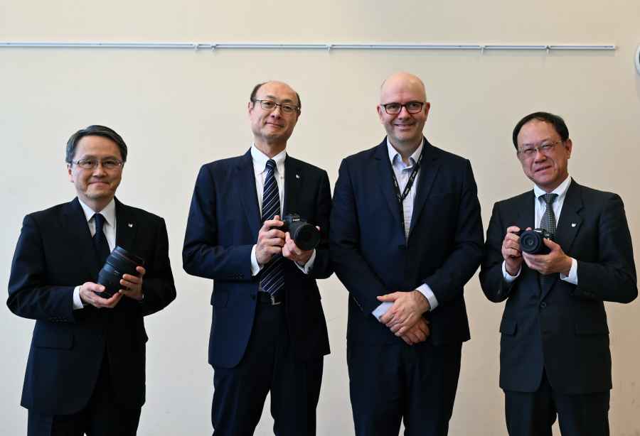 four men in suits and ties holding cameras