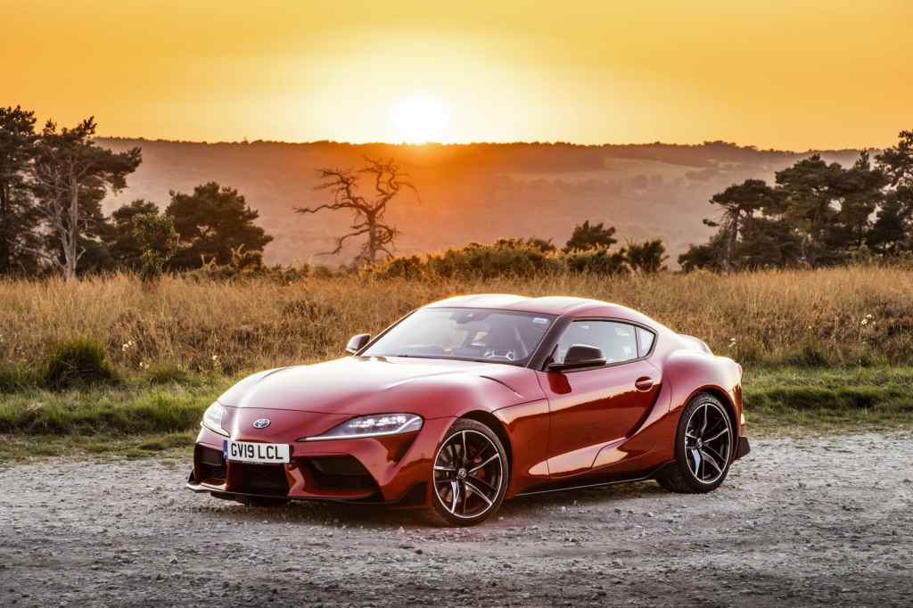 sample image from Canon EOS 90D, red sportscar at sunset against a tall grass and trees 