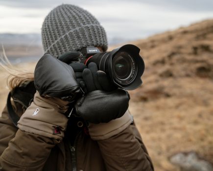 Woman in a grey knitted hat holding a camera to her face