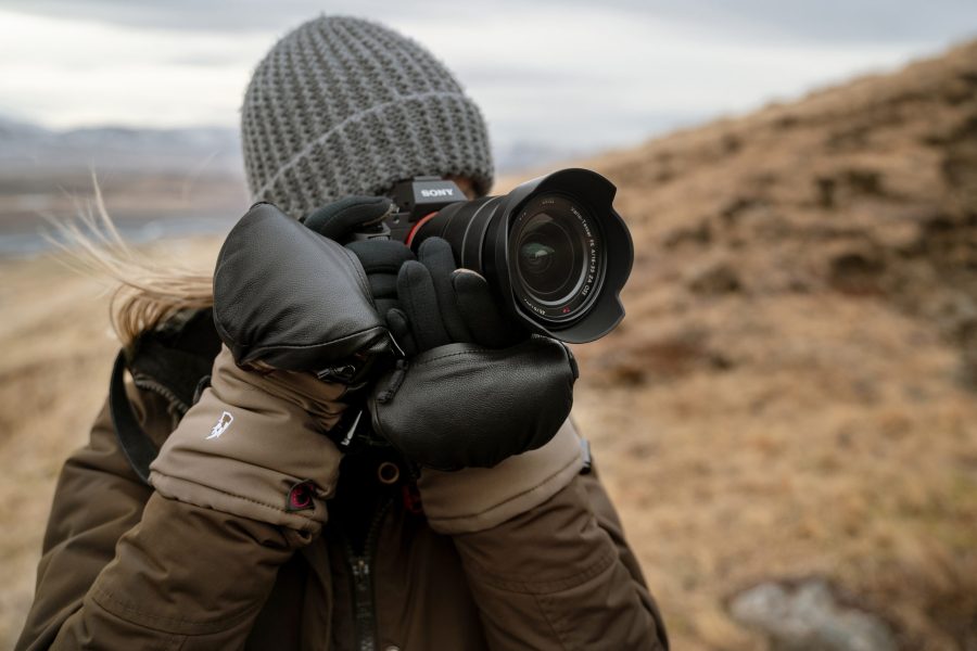 Woman in a grey knitted hat holding a camera to her face