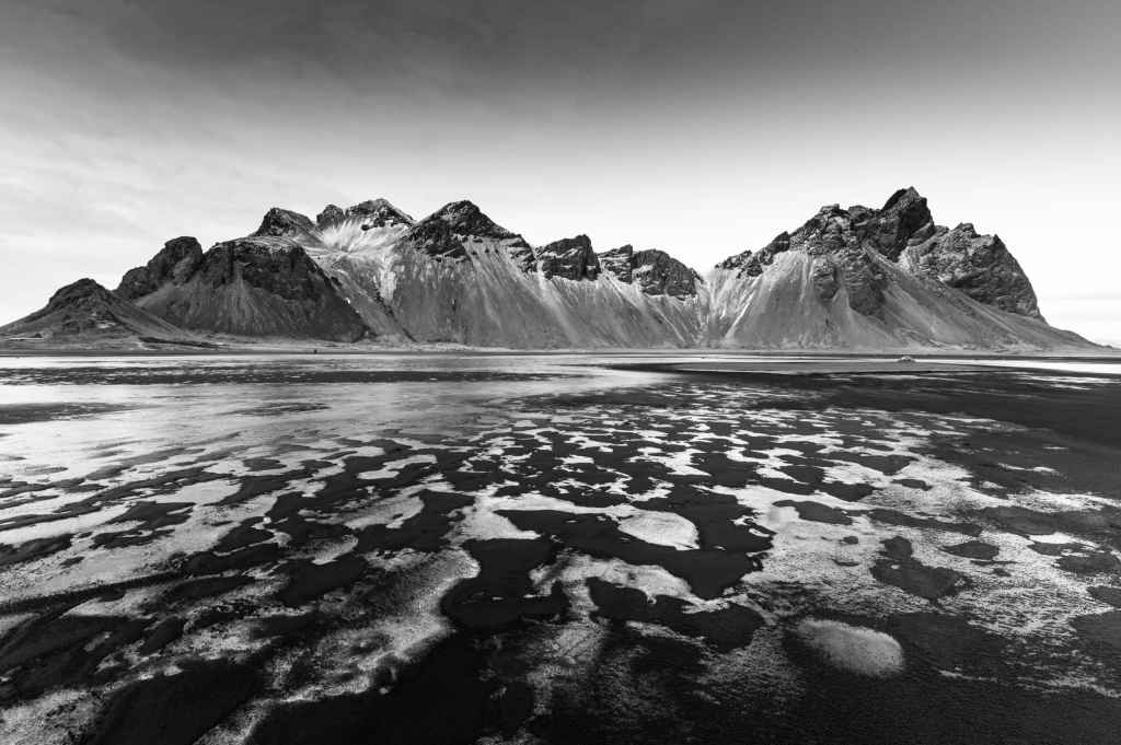 mountain range with water and sand in the foreground