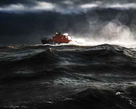 A red boat floating in the sea in really choppy, dark conditions