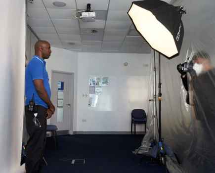 Man in a bright blue tshirt facing right in a photography studio