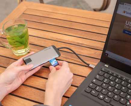 Close up of hands plugging a storage device into the side of a laptop