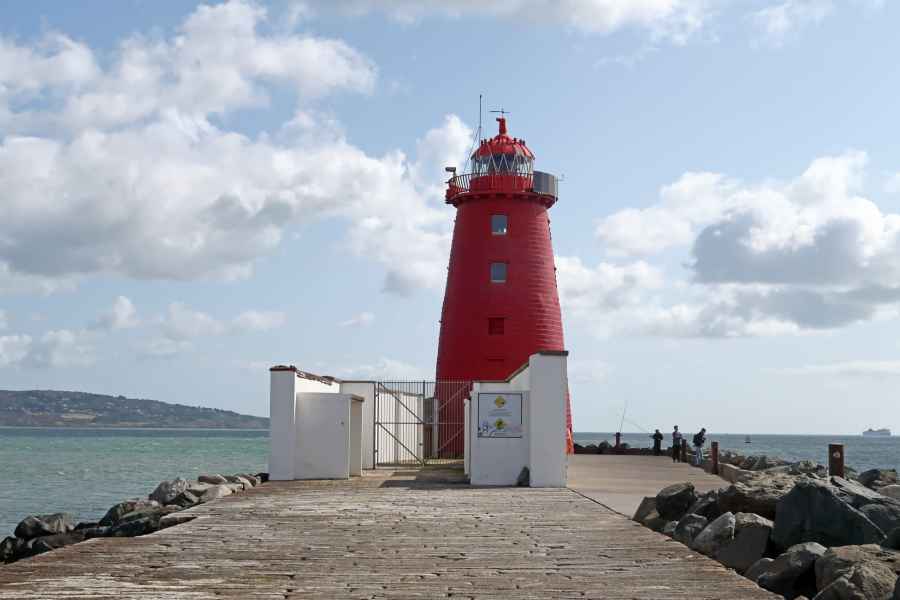 Poolbeg red lighthouse at the end of a stone path with a coastal backdrop