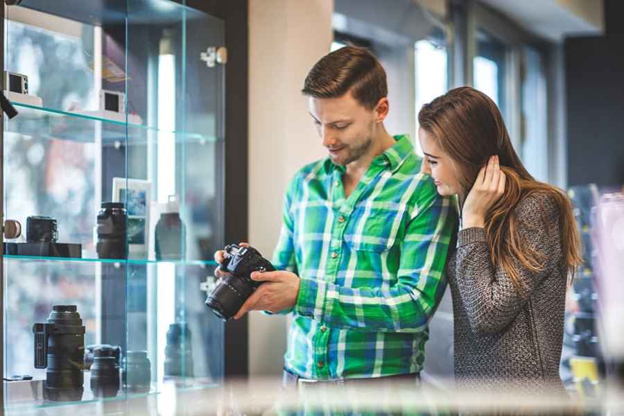 A man in a green check shirt and a woman in grey admiring a camera in a photography store