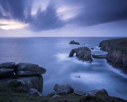 Storm approaches Enys Dodnan Arch, the Armed Knight rock, and Longg Ships lighthouse at Land's End, Cornwall, UK. September 2016.
