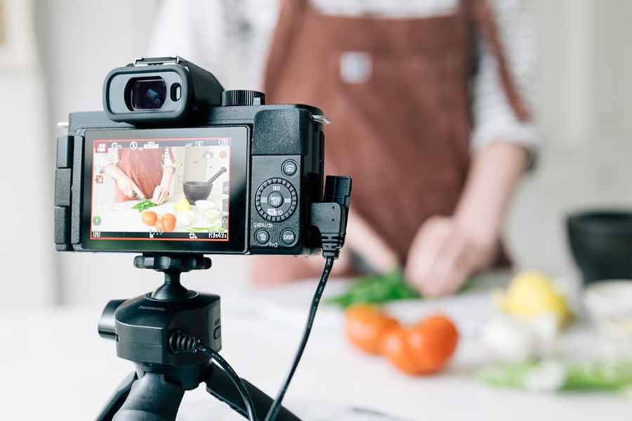 Panasonic Lumix G100 on a tripod filming someone cooking behind