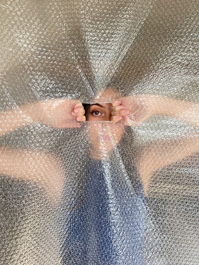 a girl peering her eye through a hole in bubble wrap smartphone photos