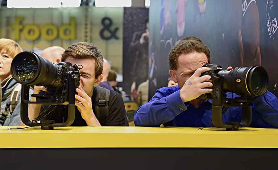 Two men behind a table testing Nikon cameras