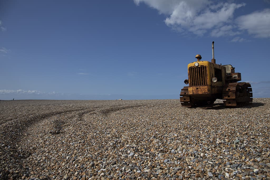 Rusty yellow tractor on pebbly beach