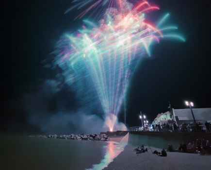 night scene taken on a smartphone of blue and red fireworks taken from a beach