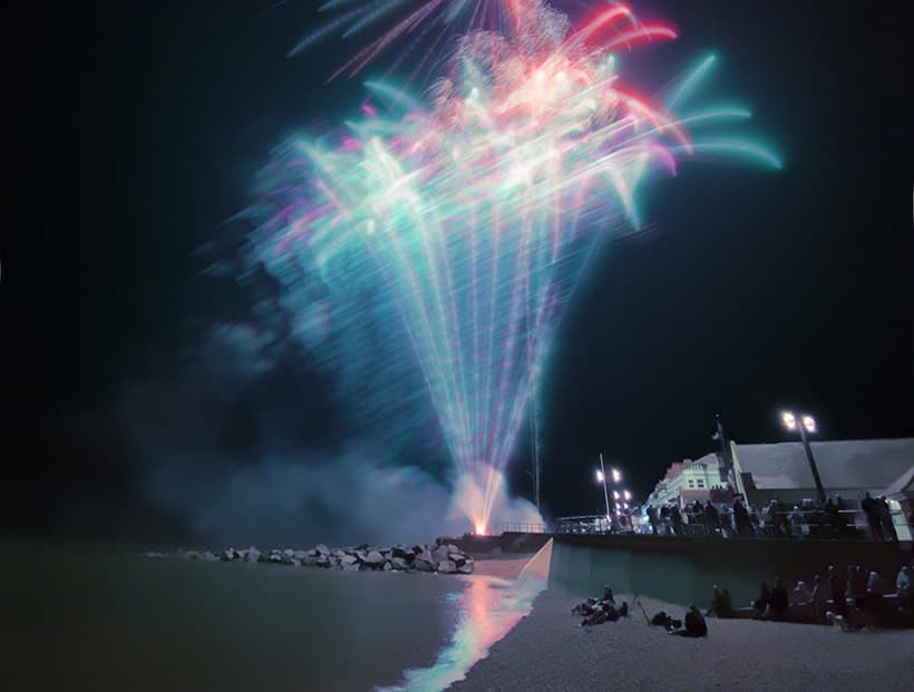 night scene taken on a smartphone of blue and red fireworks taken from a beach