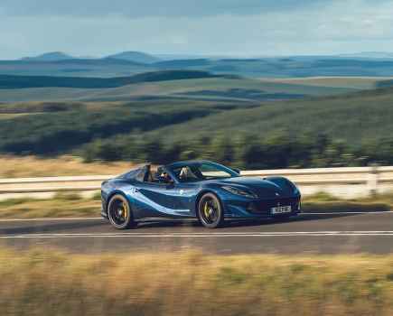 A blue Ferrari 812 GTS driving on a tarmac road in the countryside