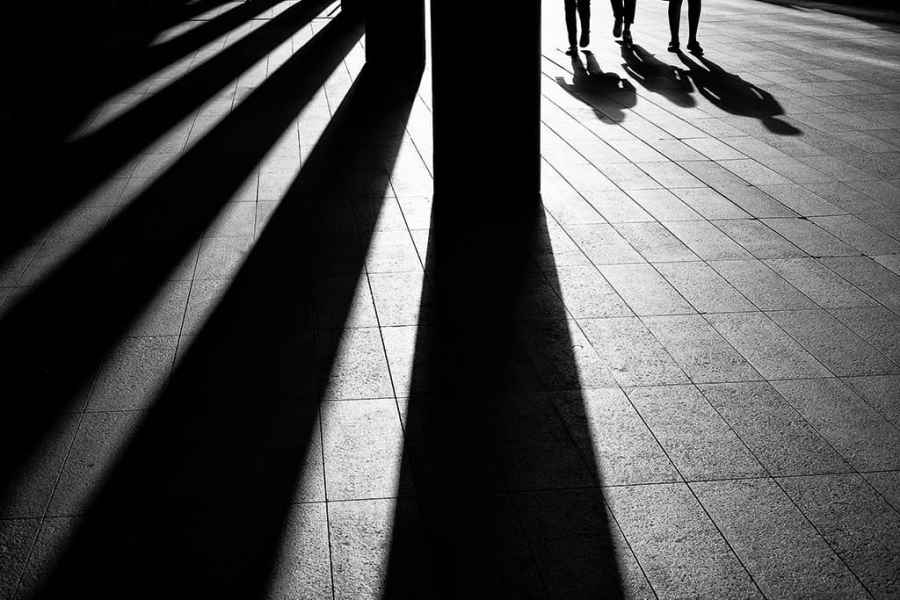 Black and white shot of shadows casted by a line of pillars