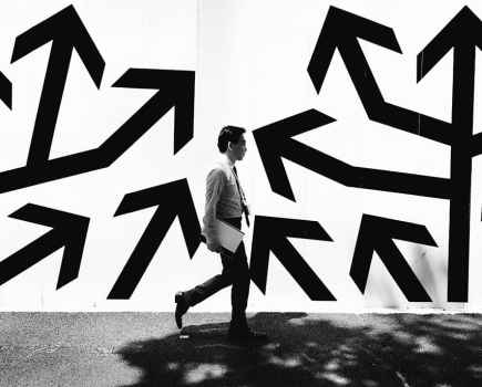 business man walking past a wall with large arrows on