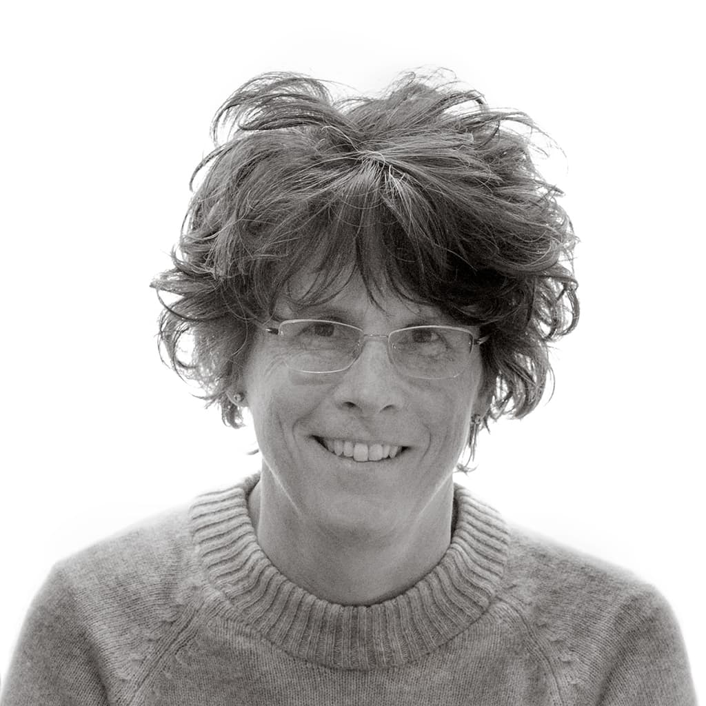 A short haired woman in glasses and a knitted jumper smiling