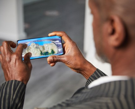 Dr. Willard Wigan MBE views his Mount Rushmore needle sculpture after photographing it with the OPPO Find X3 Pro smartphone