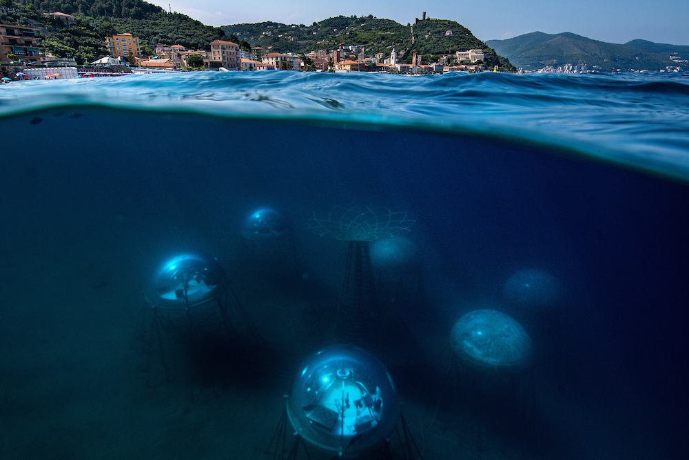 The Nemo's Garden seen from the water surface. The biospheres are located 40 metres off the Noli shore, a small village of the Ligurian coast. This particular distance has been chosen to make the biospheres more accessible for operations which requires human intervention. Their depth instead lies between 6 and 12 metrws to enable the plants to draw on the necessary source of light for their development. In the centre stands the tree of life. Under its platform the cables used for connecting the electronic devices are separated and distributed to each biosphere. Figuratively it also represent the core of the experiment: the possibility to grow terrestrial plants underwater. © Giacomo d'Orlando, Italy, Finalist, Professional, Environment, 2022 Sony World Photography Awards