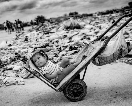 A young girl being transported home by her dad along the garbage site, on the abandoned airstrip outside Maicao in Colombia. More than 8.5 million people in Colombia urgently need help. The financial collapse in Venezuela has left many with no access to emergency aid, shelter, clean drinking water or food. Children pay the highest price. © Jan Grarup, Denmark, Finalist, Professional, Documentary Projects, 2022 Sony World Photography Awards