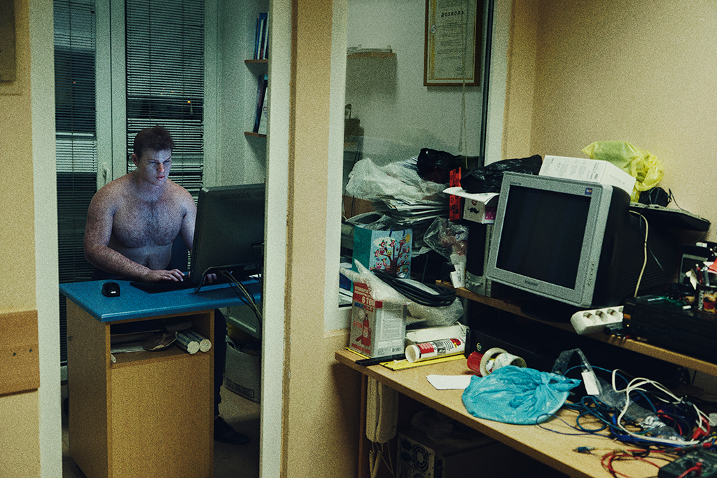 Bare-chested man at computer from fake news The Book of Veles book