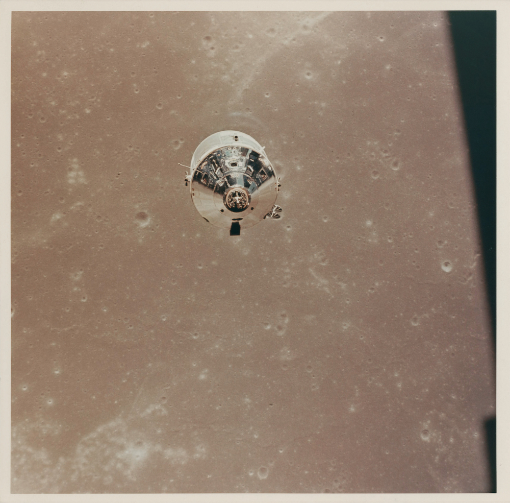 The Command and Service Module (CSM) Columbia over the Sea of Fertility, as seen from the LM descending to the lunar surface
