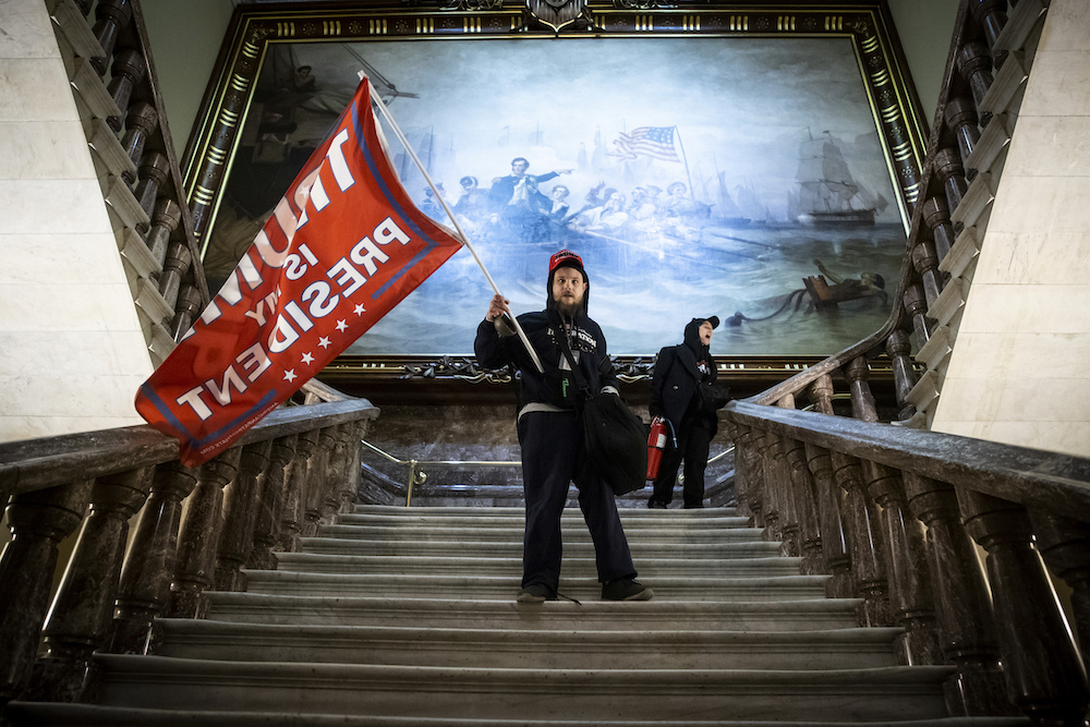 A supporter of former US President Donald Trump waves a Trump flag while descending a staircase at the US Capitol on January 6, 2021 in Washington, DC. © Win McNamee, USA, Finalist, Professional, Documentary Projects, 2022 Sony World Photography Awards