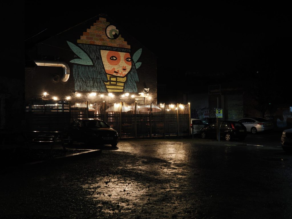 Handheld IS shot of a colourful wall mural at a car park at night.