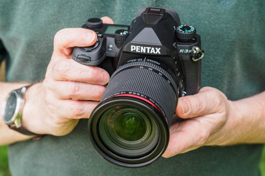 Pentax K-3 III in hand, DSLR in hand with lens