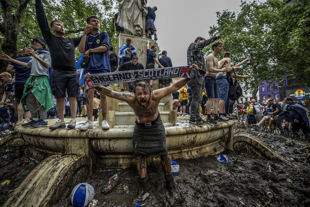 A drunken Scottish football fan stands holding a scarf in the muddy surroundings of the William Shakespeare Statue in the West End of London ahead of the EURO2020 football match between national rivals England and Scotland, 18 June 2021. © Jeff Gilbert/SJA Sports Journalism Awards
