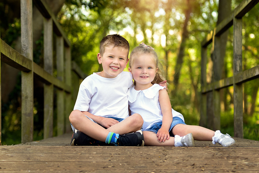 spring photo shoot with two young children sat on a bridge
