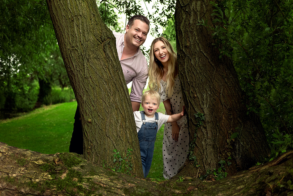 young family spring portrait behind two trees