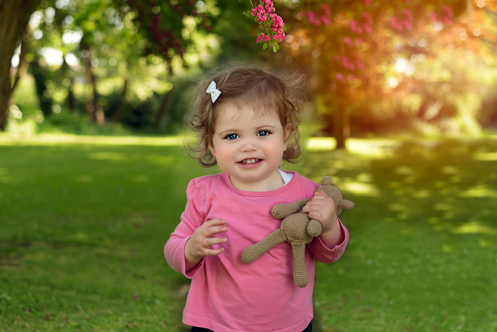 young toddler with a small brown bear in hand spring photo tips