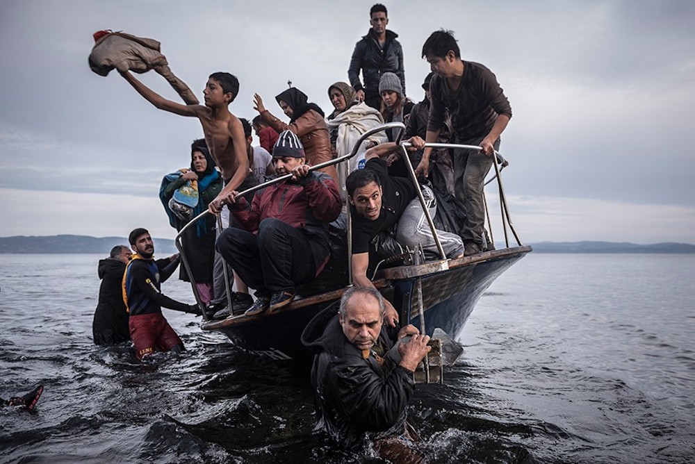 Migrants arrive by a Turkish boat near the village of Skala, on the Greek island of Lesbos. The Turkish boat owner delivered some 150 people to the Greek coast and tried to escape back to Turkey; he was arrested in Turkish waters. Part of a series of images of struggling refugees that won the 2016 Pulitzer Prize for Breaking News Photography Tyler Hicks, Daniel Etter, Sergey Ponomarev and Mauricio Lima of The New York Times. Image: Sergey Ponomarev/The New York Times