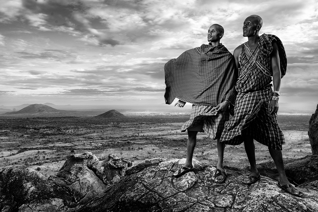 black and white photo of two mean standing on rock